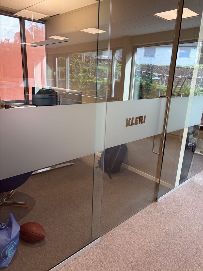 Frostet folie med Kleri-logo på glassvegg
